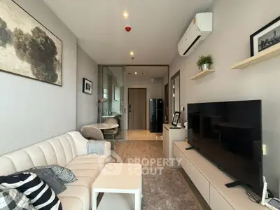 Modern living room with stylish decor, air conditioning, and open layout leading to kitchen area.