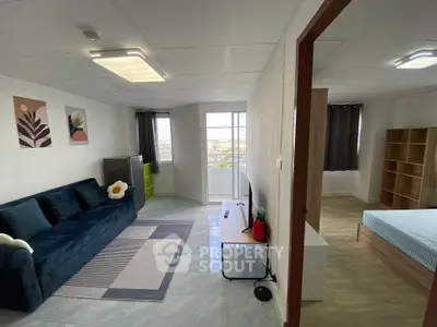 Modern apartment interior with stylish living room and bedroom, featuring a cozy blue sofa and large windows.