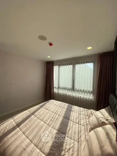 Bright bedroom with large window and elegant curtains, showcasing natural light and cozy ambiance.