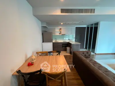 Modern open-plan living room with stylish kitchen and dining area in contemporary apartment.