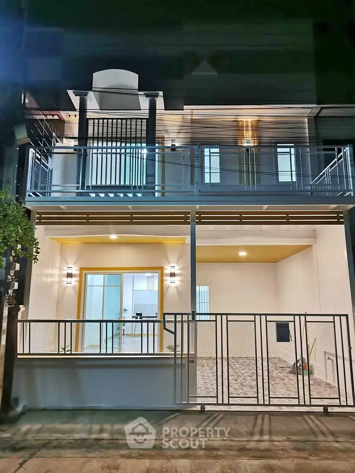 Modern two-story house with sleek balcony and illuminated facade at night
