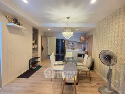 Stylish dining area with elegant chandelier and modern kitchen in open layout apartment.