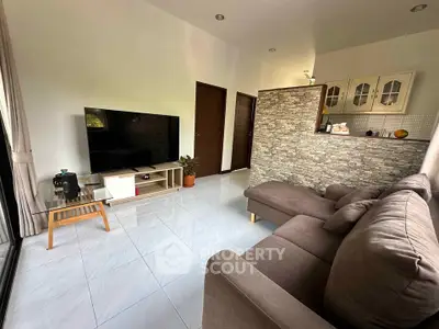 Spacious living room with modern decor and large TV, perfect for relaxation.