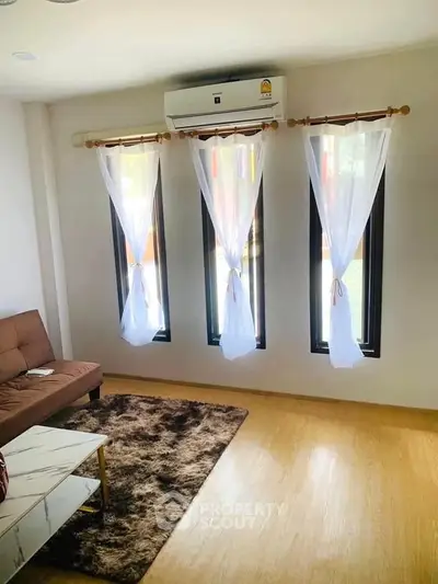 Bright living room with modern decor and large windows, featuring a cozy sofa and stylish rug.