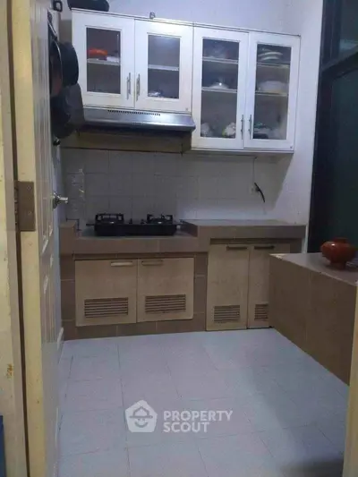 Compact kitchen with closed layout and gas stove, featuring modern cabinets and tiled flooring.