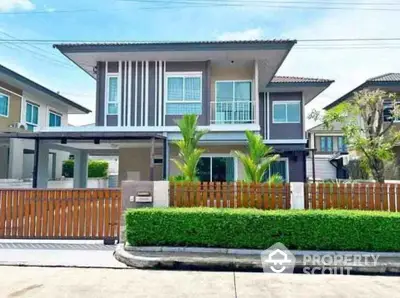 Modern two-story house with lush greenery and wooden fence in suburban neighborhood.