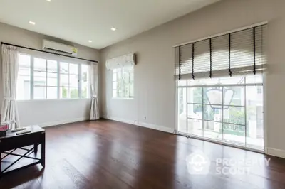 Spacious empty living room with large windows and hardwood floors