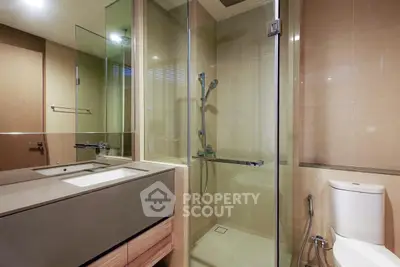 Modern bathroom with glass shower and sleek vanity in luxury apartment.