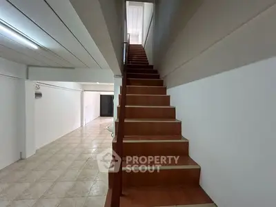 Spacious interior with tiled flooring and wooden staircase, ideal for modern living.