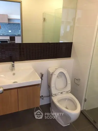 Modern bathroom with sleek fixtures and glass shower in contemporary apartment.
