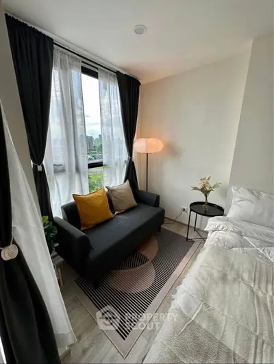 Cozy bedroom with modern decor, featuring a stylish sofa and large window with city view.