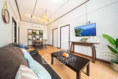 Stylish living room with modern decor, wooden flooring, and wall-mounted TV in a cozy apartment.