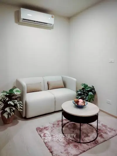 Cozy living room with modern sofa, air conditioning, and stylish decor plants.
