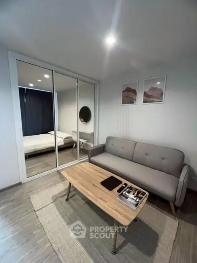 Modern living room with sleek sofa, mirrored closet, and stylish decor in a cozy apartment.