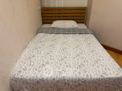 Cozy bedroom with a neatly made bed and wooden headboard, perfect for restful nights.