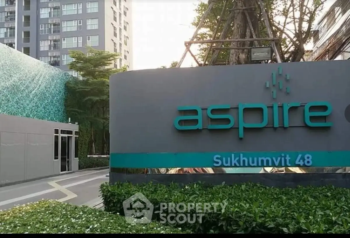 Modern residential building entrance with lush greenery and stylish signage.