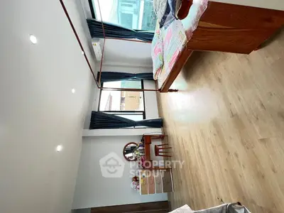 Spacious bedroom with large windows and wooden flooring