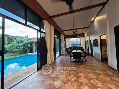 Stunning open-plan living room with pool view, high ceilings, and modern design in a luxurious home.