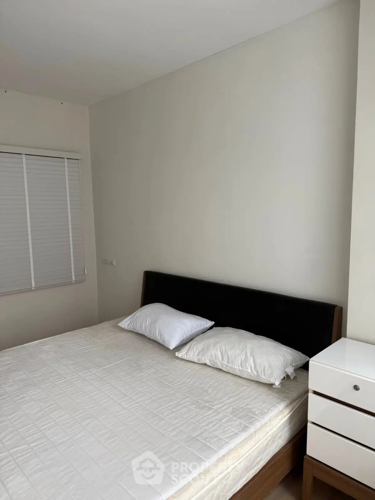 Cozy bedroom with modern bed and nightstand, perfect for relaxation.