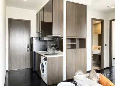 Modern compact kitchen with integrated appliances and wooden cabinetry, seamlessly blending with a cozy living space, perfect for urban living.