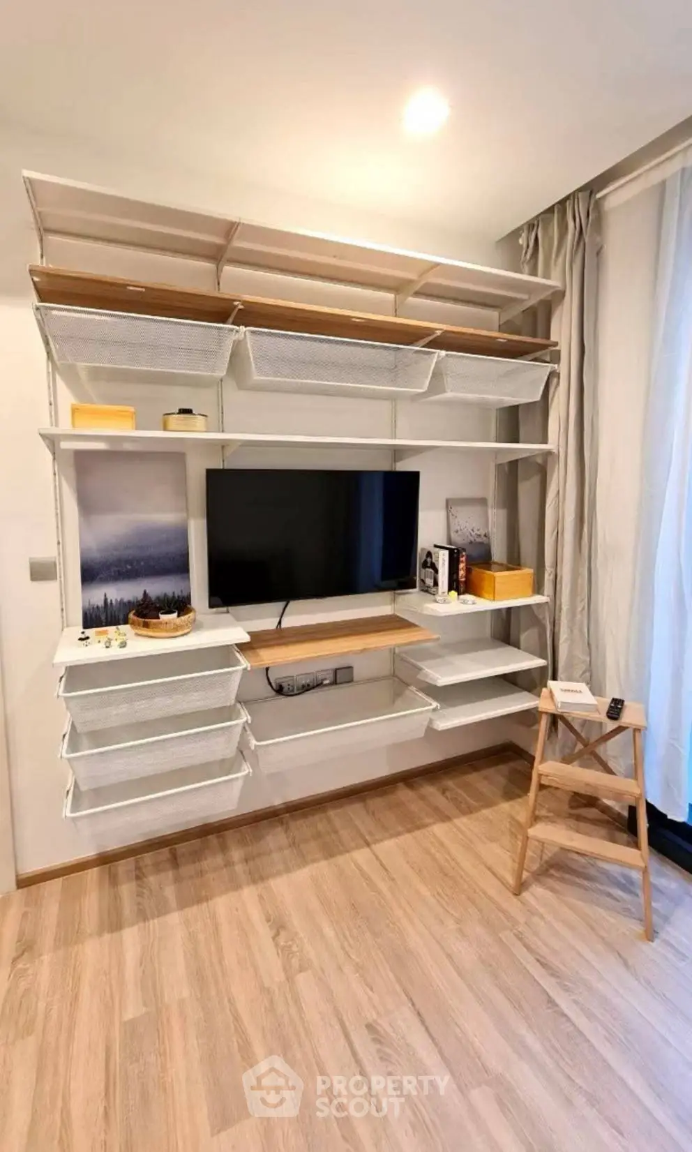 Modern living room with stylish shelving and TV setup, featuring elegant wooden flooring and natural light.