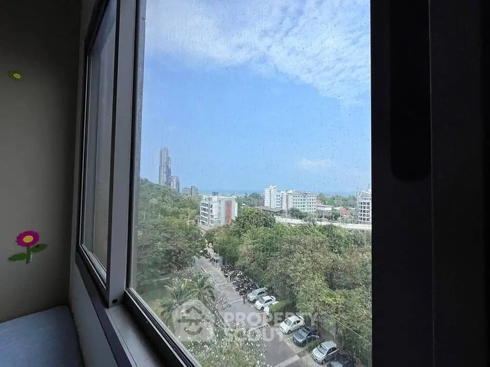 Stunning cityscape view from a high-rise window with lush greenery and urban skyline.