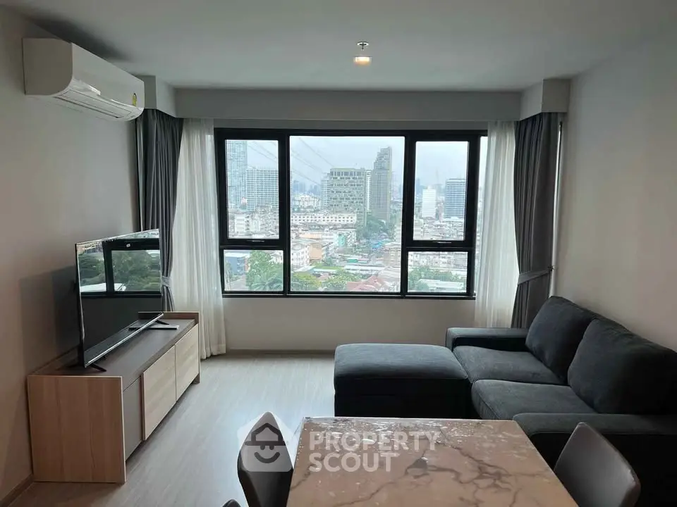 Modern living room with city view, featuring sleek furniture and large windows for natural light.