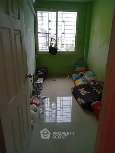 Cozy small bedroom with green walls and large window, ideal for compact living.