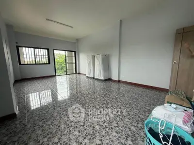 Spacious empty room with tiled flooring and large windows offering natural light.