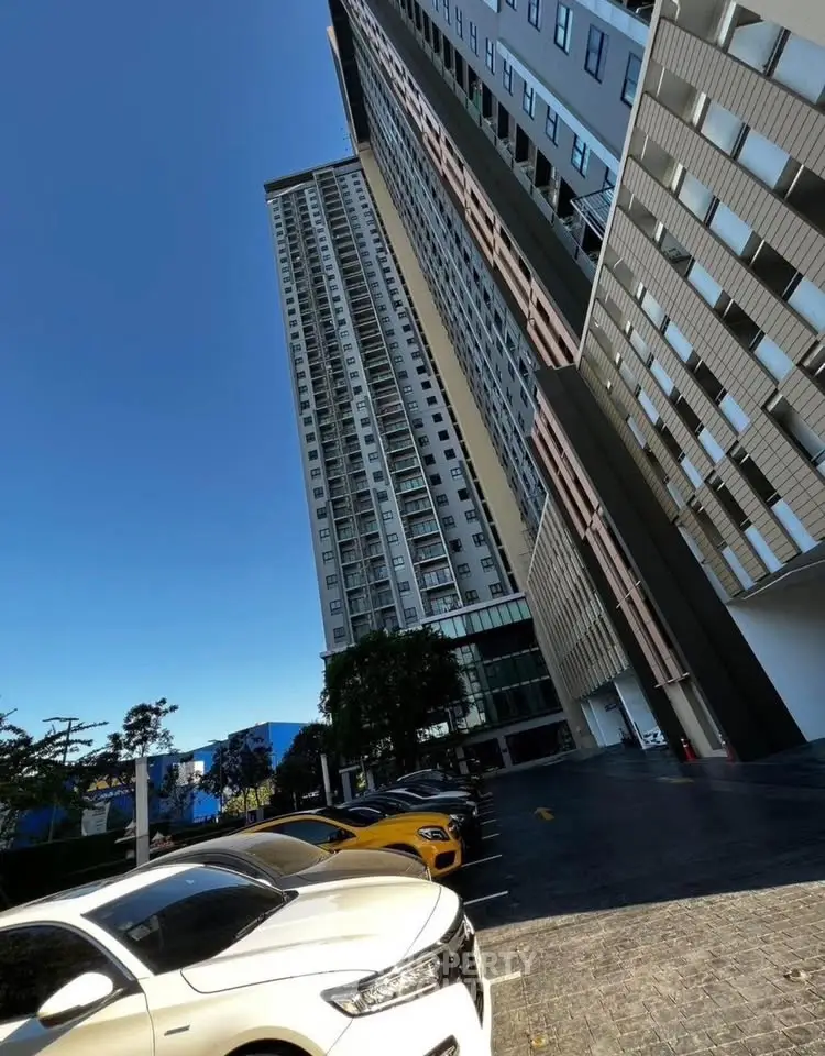 Modern high-rise building with sleek architecture and spacious parking area.