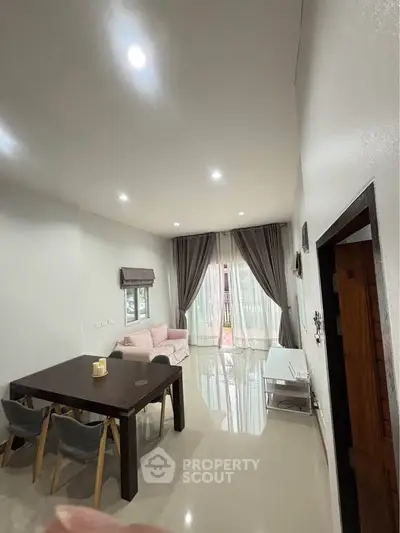 Spacious living room with high ceiling and elegant decor, featuring a cozy seating area and dining table.