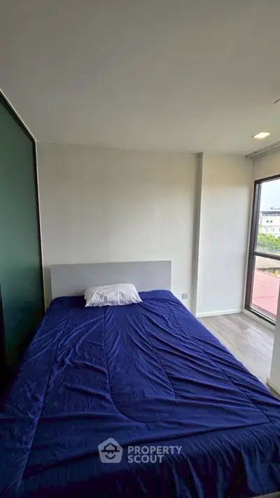 Cozy bedroom with large window offering natural light and modern design.