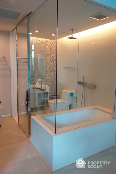 Modern bathroom with glass shower and built-in bathtub in luxury apartment