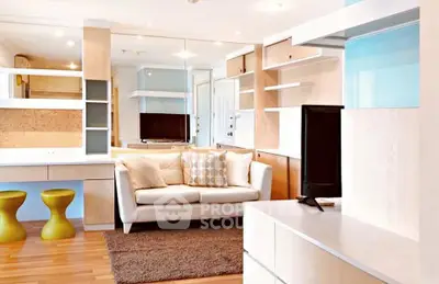 Modern living room with stylish furniture and open shelving, featuring a cozy sofa and sleek TV setup.