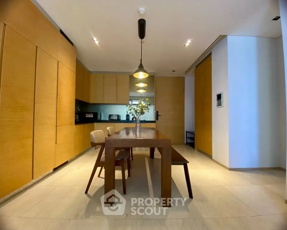 Modern dining area with sleek wooden furniture and stylish lighting in a contemporary home.