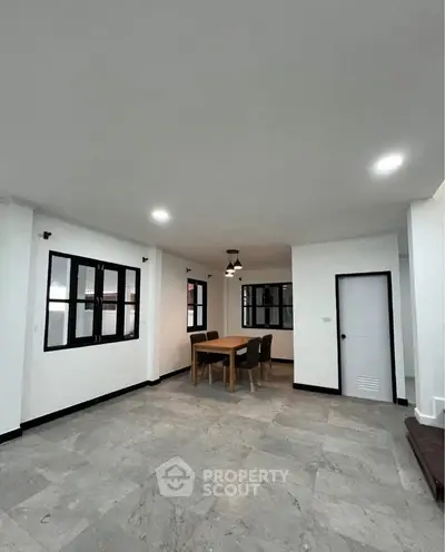 Spacious dining area with modern lighting and large windows in a contemporary home.