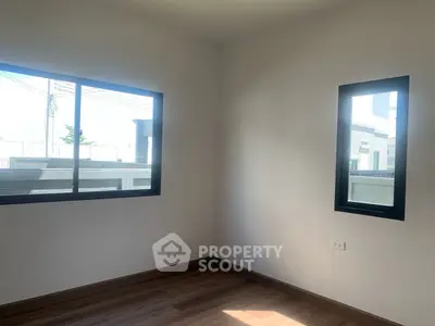 Bright empty room with large windows and wooden flooring in modern home.