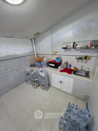 Compact kitchen with sink, storage, and organized supplies in a cozy real estate unit.
