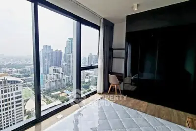 Luxurious bedroom with stunning city view from floor-to-ceiling windows in high-rise apartment.