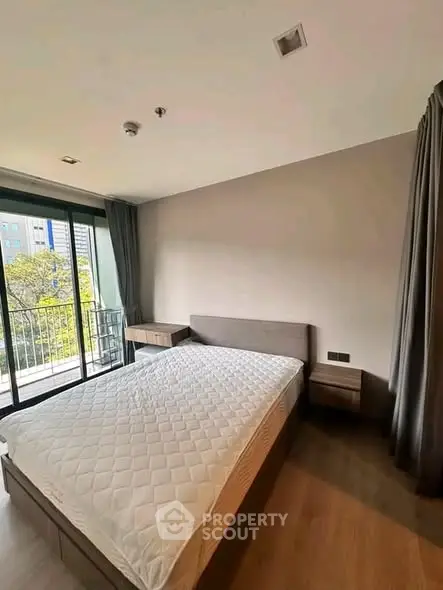 Spacious bedroom with large window and balcony access in modern apartment.