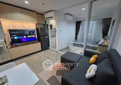 Modern open-plan living room with sleek kitchen and cozy bedroom view.