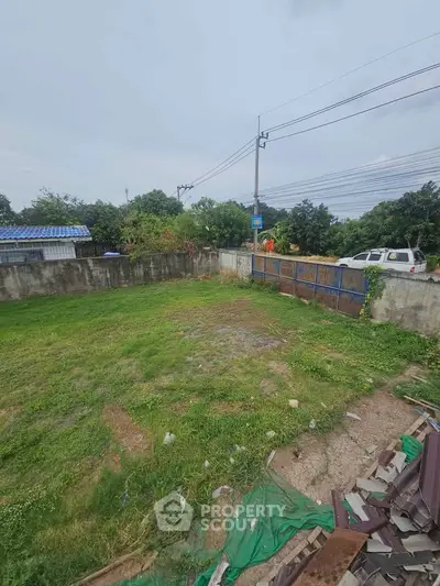 Spacious vacant land with potential for development, featuring lush greenery and a secure boundary fence.
