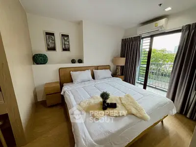 Cozy bedroom with balcony view, featuring modern decor and natural light.