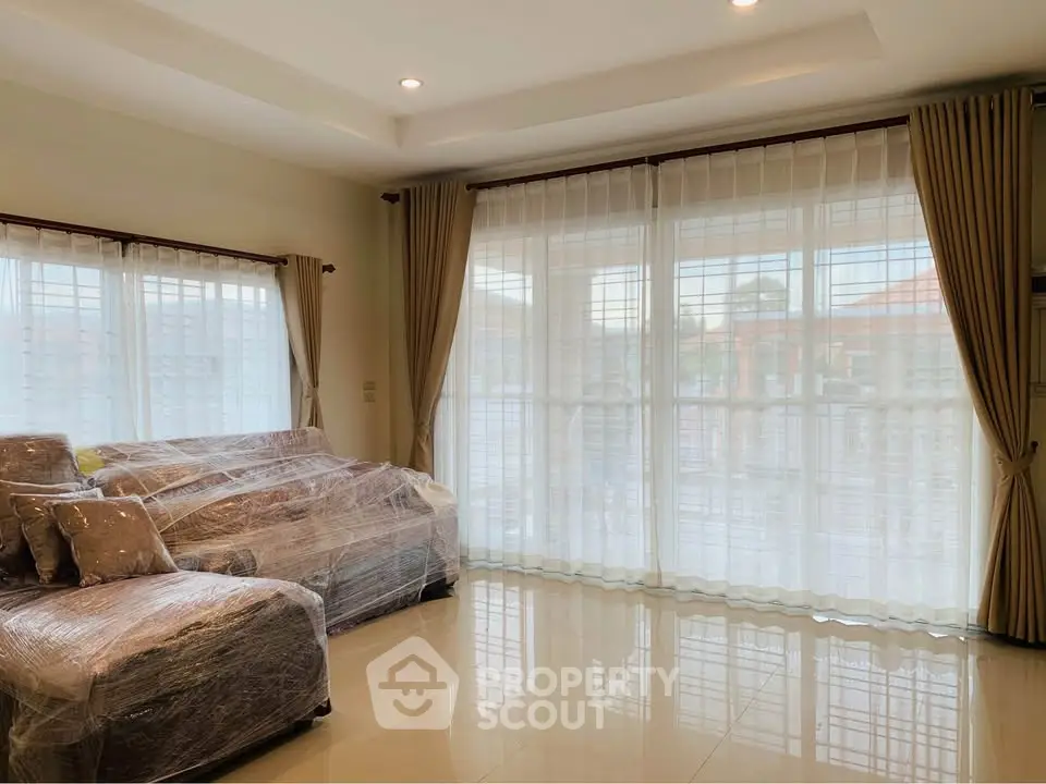 Spacious living room with large windows and elegant curtains, perfect for natural light.