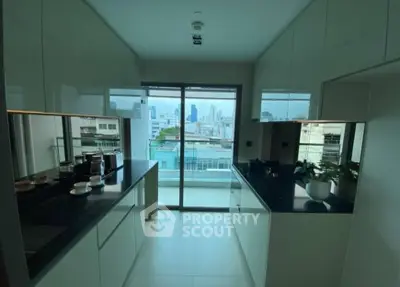 Sleek modern kitchen with high-end finishes and a stunning city view through floor-to-ceiling glass doors leading to a spacious balcony.