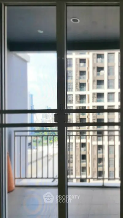 Modern apartment balcony with city view through glass doors, offering urban living experience.