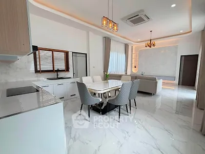 Luxurious open-plan living room and kitchen with modern decor and marble flooring.