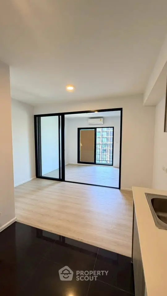 Modern apartment interior with sleek design and large glass doors leading to a balcony.