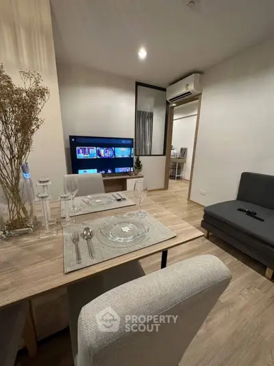 Modern living room with dining area, featuring stylish decor and a wall-mounted TV, perfect for cozy gatherings.