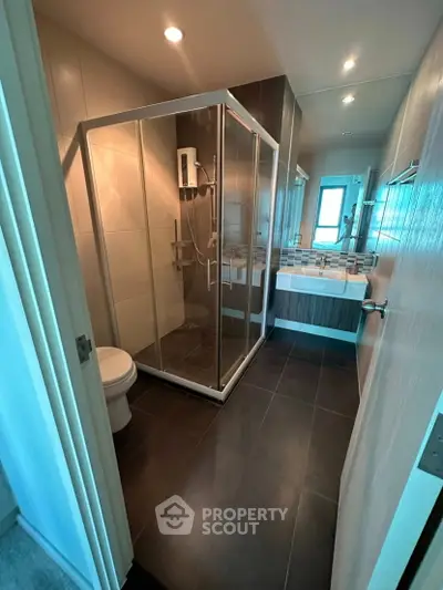 Modern bathroom with glass shower and sleek fixtures in a contemporary apartment.